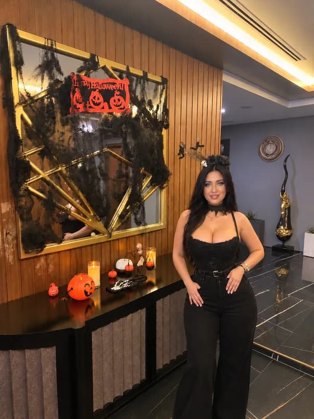 Browns Spa therapist in a black Halloween outfit and flower headband beside the spa Halloween decorations