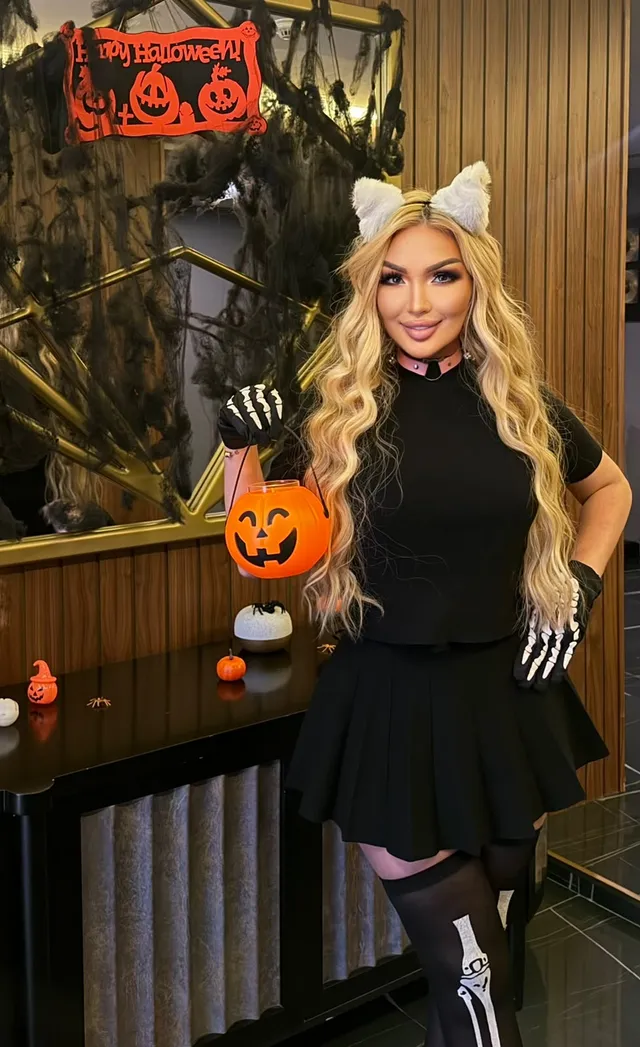 Browns Spa therapist in cat ears and skeleton gloves holding a pumpkin bucket